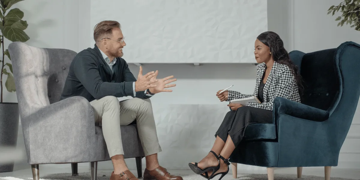 Man and woman having a relaxed supportive conversation in a bright, comfortable room